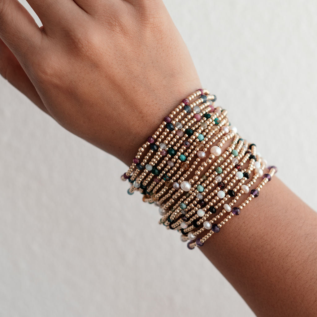 A multicolored beaded bracelet made with gemstones and metal beads, displayed on a wrist.